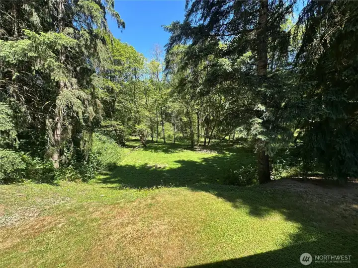 Land is cleared and slopes down to a flat useable area along the river.
