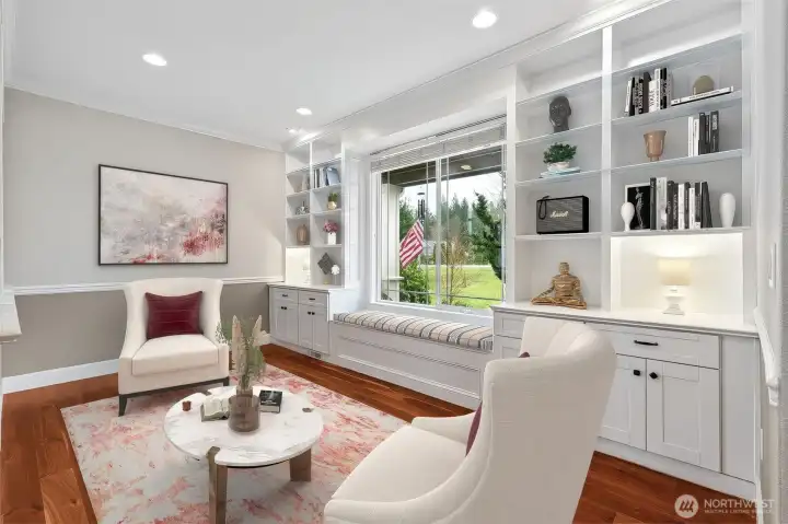 If you love a room with character, this one delivers. Floor to ceiling built-ins line the wall in crisp white, offering display space up top and hidden storage below, plus a window seat with storage underneath that practically begs for coffee, a book, or people watching from the front porch view. Cherry hardwood floors ground the space beautifully, and the chair rail with two tone neutral walls adds just enough detail without feeling formal or stuffy. It’s a great spot for a library, parlor, or a quiet escape that still feels connected to the rest of the home.