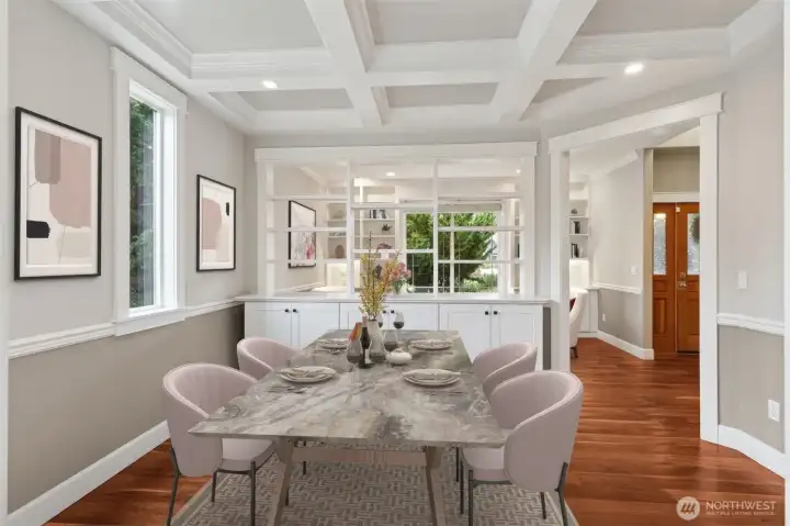This dining room brings the drama with a coffered ceiling setting the tone, paired with classic chair rail detail and two tone walls that feel polished but not too formal. A built in buffet anchors the shared wall with the parlor, making entertaining feel easy and intentional. Rich cherry hardwood floors run underfoot, while the oversized window keeps the space bright and comfortable for everyday meals or special occasions.