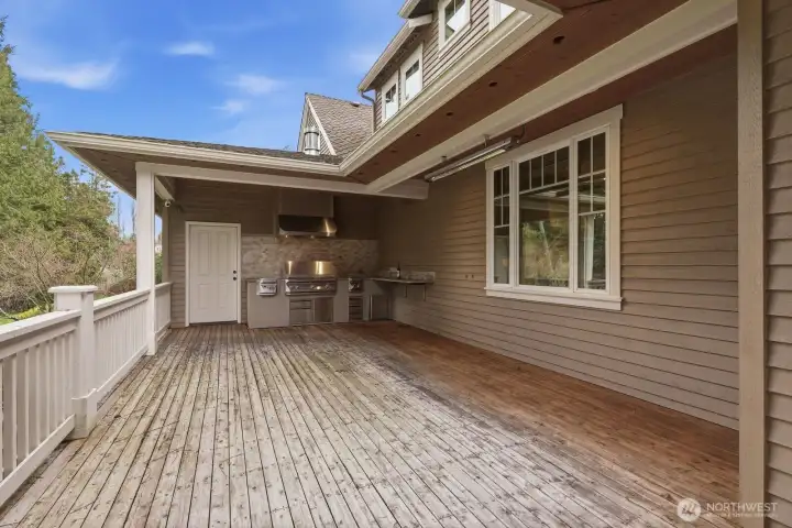 Outdoor kitchen with high end Twin Eagles BBQ, slab granite bar and electric stove burner.