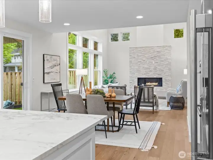 Looking from the kitchen to the eating area and great room. Covered outdoor patio located conveniently to the left. Great privacy with unbuildable green area behind the fence.