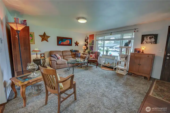 Living room with carpeted flooring, a picture big window to bring in lots of natural light, and wall heating.