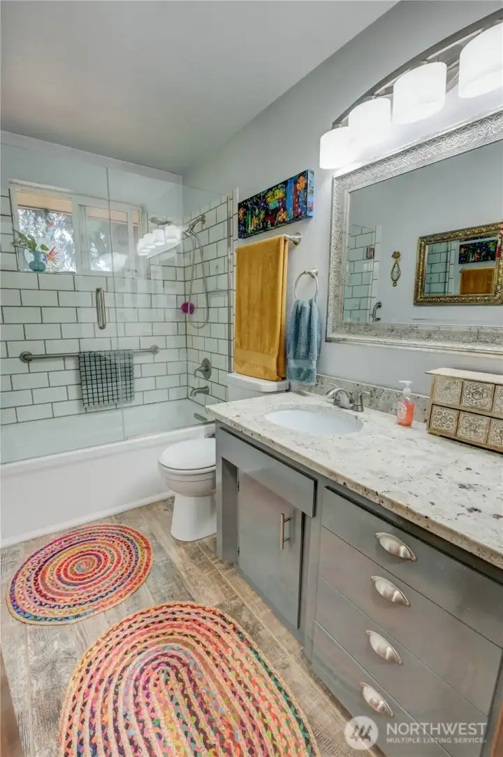 Updated full bathroom with LVP flooring, tiled shower and glass doors. Vanity offers inset sink and plenty of storage and counter space.