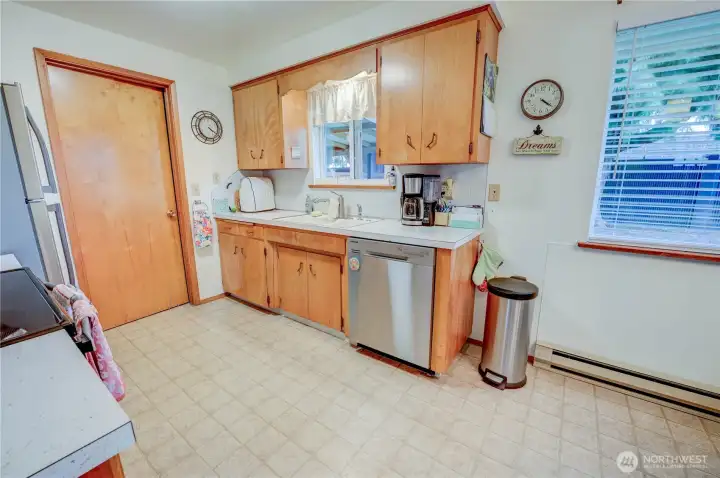 Unit 2021 Kitchen with stainless appliances and laminte floors. Door through kitchen leads into utility room and to interior garage door, plus access to backyard.