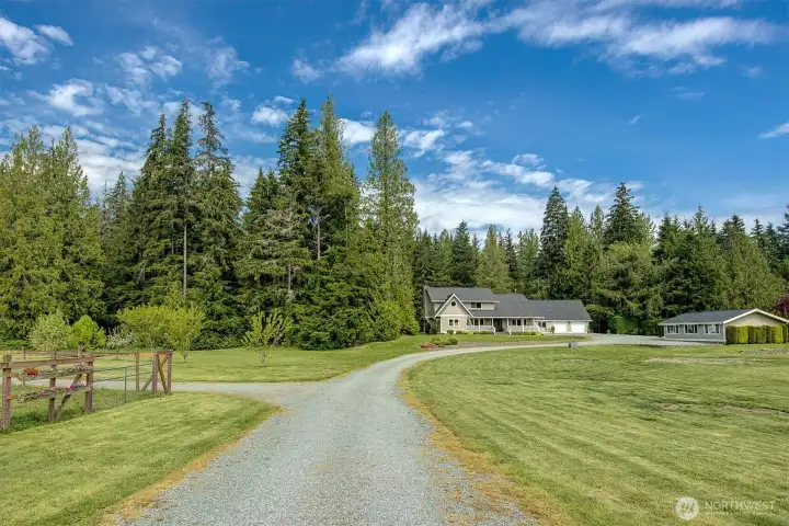 Gated driveway leads to home with access to barn on the left.