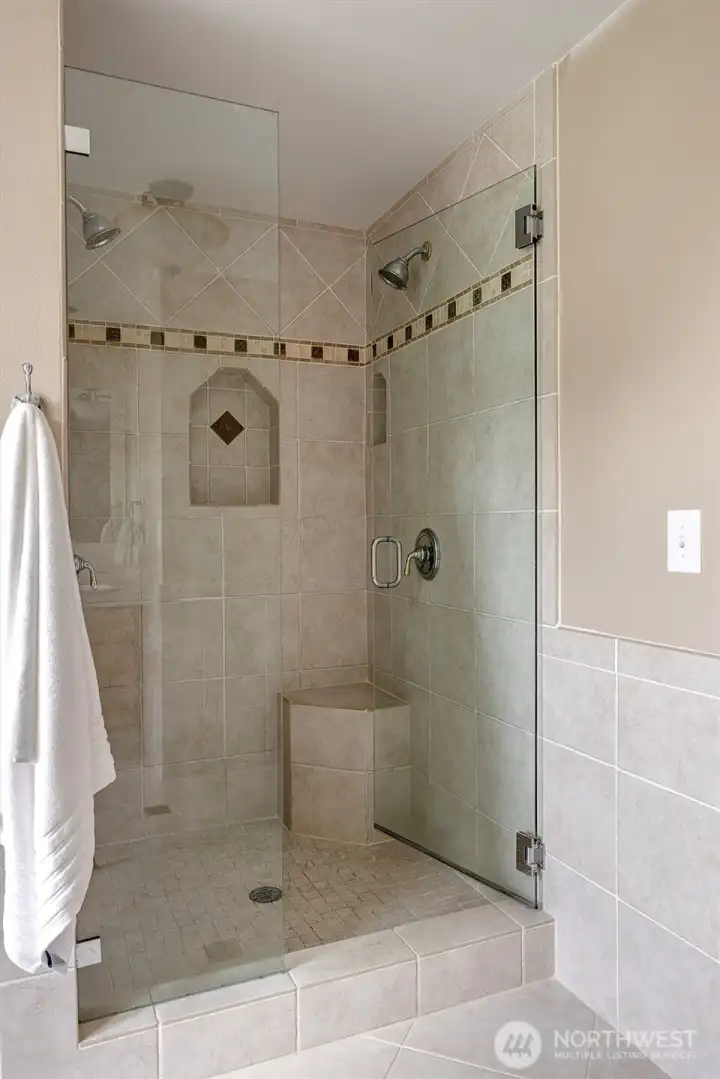 Primary Bathroom walk-in tiled shower with dual showerheads.