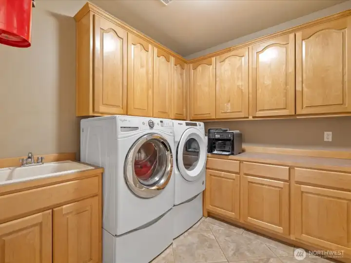 The spacious laundry room offers abundant cabinets and countertops for folding and organization. A large utility sink is perfect for pets or any messes you’d rather keep out of the kitchen.