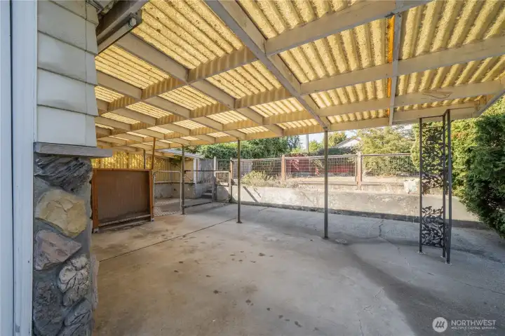 Carport attached to 1 car garage looking west in the detached fully fenced side yard.