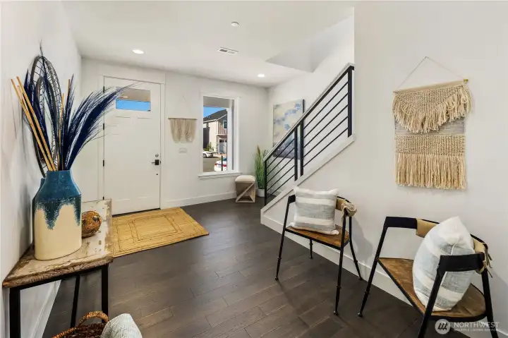 Entry  The entry sets the tone with clean architectural lines and durable wide plank flooring that carries throughout the main level. Natural light filters in through the front-facing window, while a streamlined staircase with modern railing detail adds visual contrast and contemporary character. The layout offers an open yet defined welcome into the home’s connected living spaces.    Positioned in Bothell’s Canyon Park area, this thoughtfully designed entry reflects the quality and attention to detail found in Pacific Northwest contemporary homes. The inviting flow supports everyday function within a well-crafted new construction residence located in the Northshore School District.    These photos are from a past Robinson Plan at a different community, so overall plan, colors, building orientation, finishes, home outlook, and other details can and WILL vary. All photos, renderings, site maps, and floorplans are for visualization purposes only.