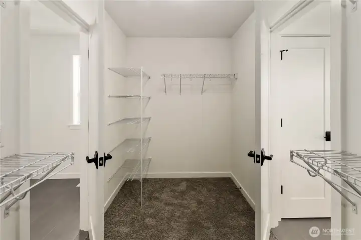 Walk-In Closet with Direct Laundry Access  This spacious walk-in closet offers dedicated storage with built-in shelving and an efficient layout designed for organization. Neutral finishes and durable carpeting create a clean, functional environment, while the generous proportions allow for flexible wardrobe configurations.    Positioned between the primary bathroom and laundry room, the pass-through design provides direct laundry access for added convenience. Located in Bothell’s Canyon Park area, this thoughtful feature reflects the smart planning associated with contemporary new construction homes served by the Northshore School District.    These photos are from a past Robinson Plan at a different community, so overall plan, colors, building orientation, finishes, home outlook, and other details can and WILL vary. All photos, renderings, site maps, and floorplans are for visualization purposes only.