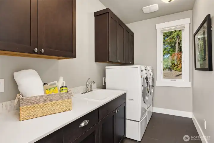Convenient upper-level laundry with a utility sink and plenty of built-in storage.
