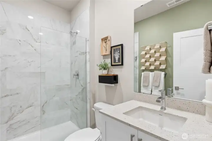 Main-level guest bath with quartz counters and tiled shower.  Photos are representational only.