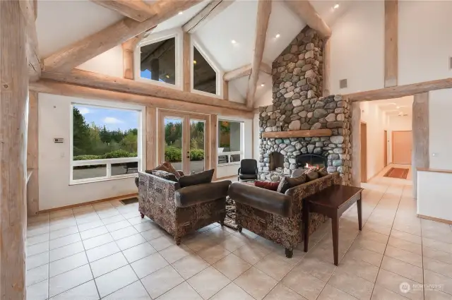 Open-concept family room with massive windows, French doors and natural river rock fireplace.