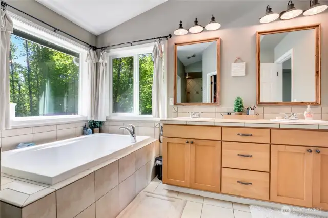 Primary bath with soaking tub, double vanity, walk-in closet and walk-in shower with multiple heads.