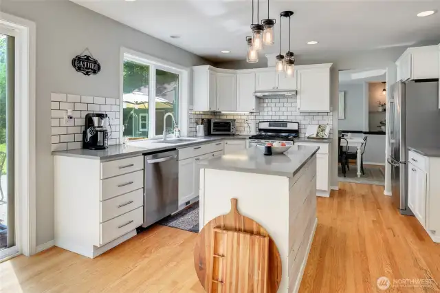Kitchen with stainless appliances, quartz countertops, subway backsplash and hardwood floors.