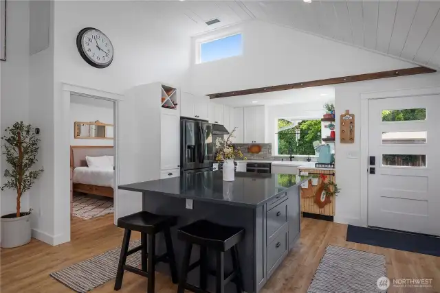 Large kitchen island with quartz countertops & pull out spice and wastebasket cabinets.