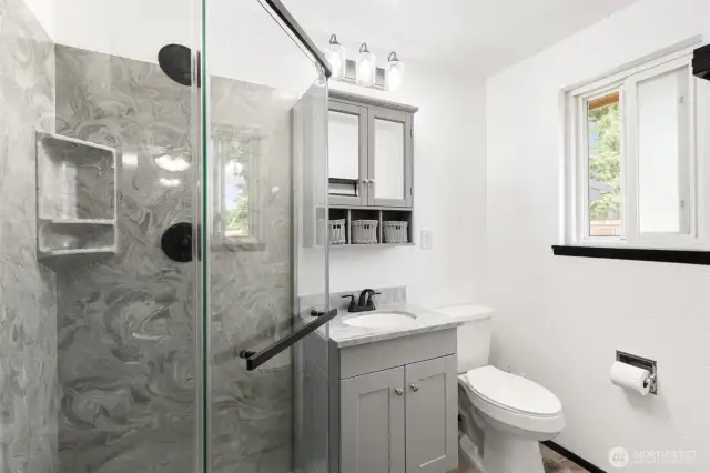 Primary bedroom quarter bathroom shower, vanity and toilet seat with window and storage