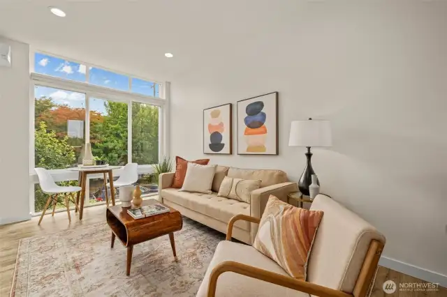 Sunlight filters through the large windows, highlighting the open and inviting living room