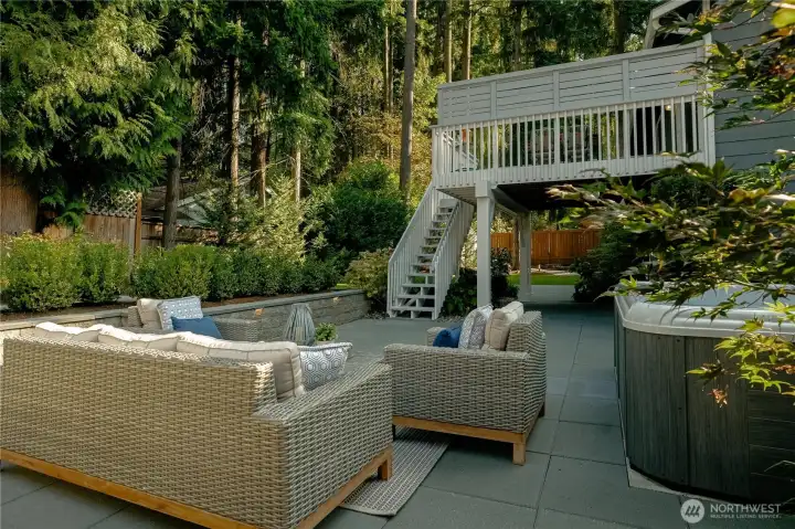 Outdoor living space with extensive hardscape. Seating area and hot tub.