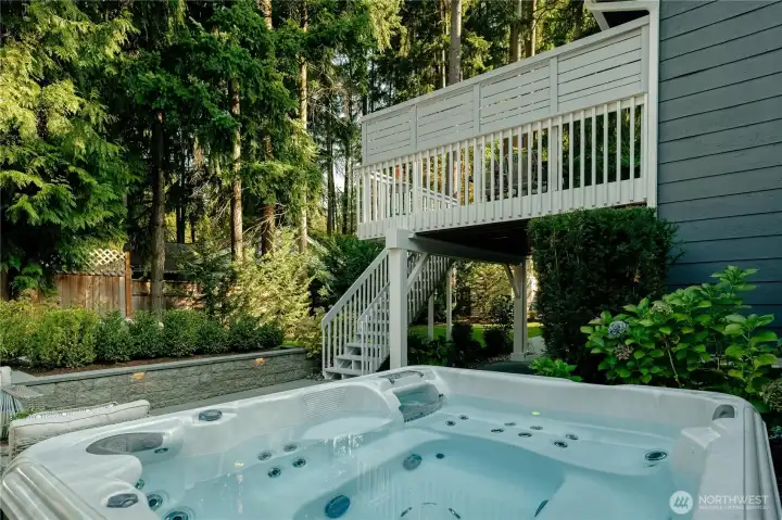Eight person hot tub surrounded by privacy fencing and mature landscaping