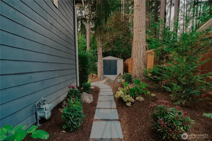Landscaped side yard leads to garden shed and backyard.