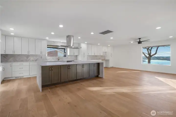 A view into the kitchen and dining room with quartz waterfall island and counters.