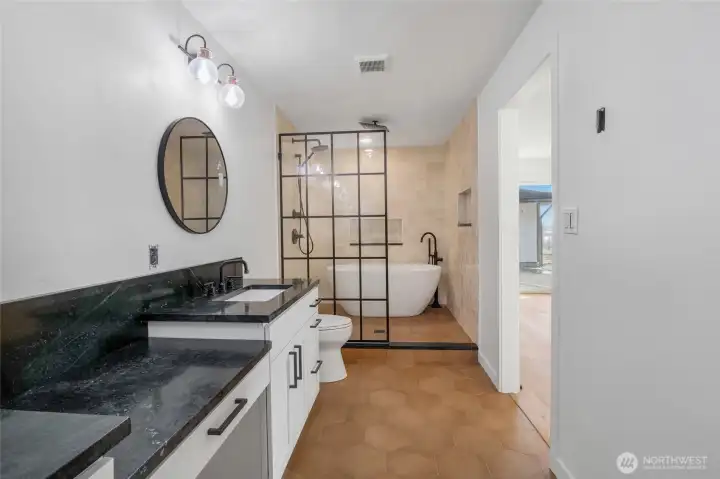 The remodeled primary bath features dual sinks, a high-end soaking tub, and an expansive shower with multiple showerheads, all set within a refined, spa-like space.