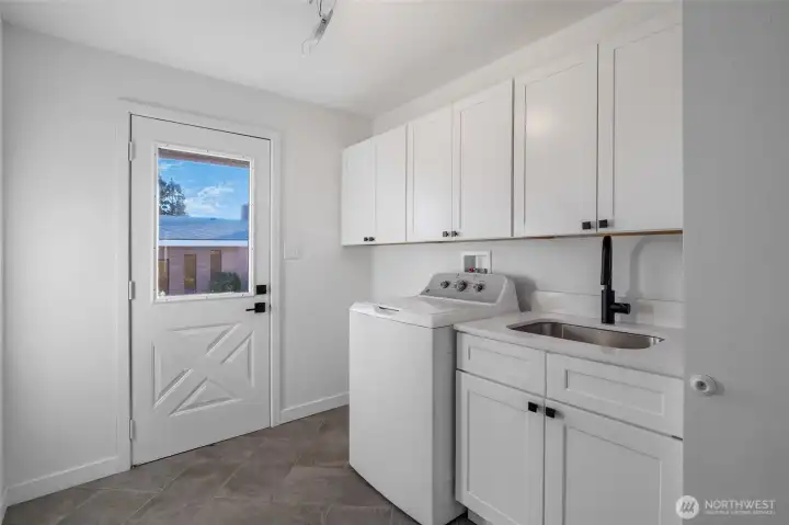 The utility room boasts a number of cabinets for all of your laundry, cleaning, and pet supplies, with room to place coat hooks and a bench for slipping your shoes on.