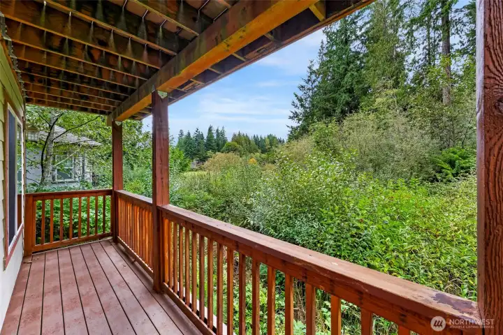 Covered deck off the living room overlooks the backyard and nearby Lake Louise area, offering a peaceful outdoor space to enjoy morning coffee or evening relaxation.