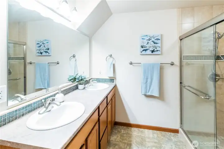 Primary bath features a double-sink vanity with ample counter space and storage, plus a large mirror and bright overhead lighting.