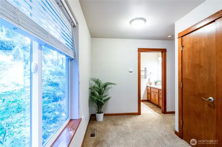 Upstairs hallway with large window bringing in natural light, leading toward the main bathroom that serves the secondary bedrooms.