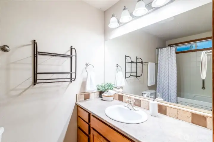 Main bathroom vanity with generous counter space, large mirror, and bright lighting.