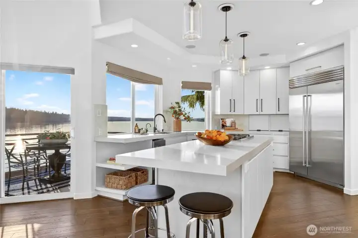 A chef's kitchen with high-end appliances, herringbone backsplash, and a wall of windows framing the lake — equal parts functional and stunning.