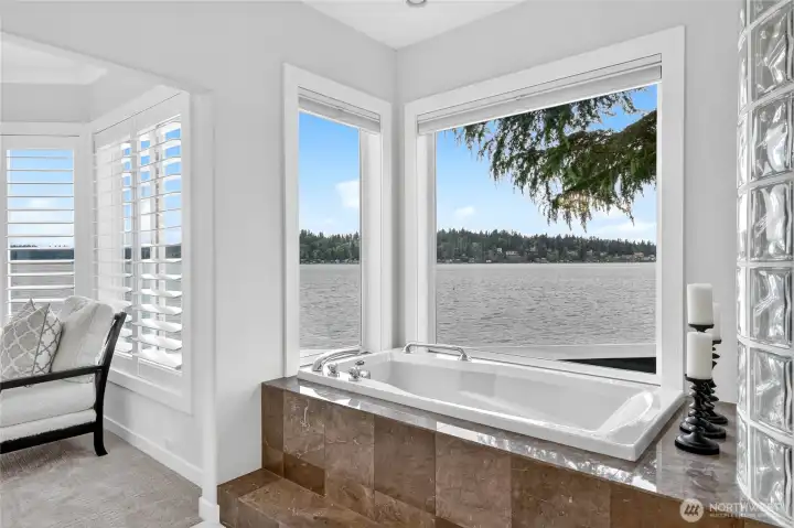 A spa-caliber primary bath with vessel sinks, rich marble countertops, and a soaking tub positioned to capture the lake view.