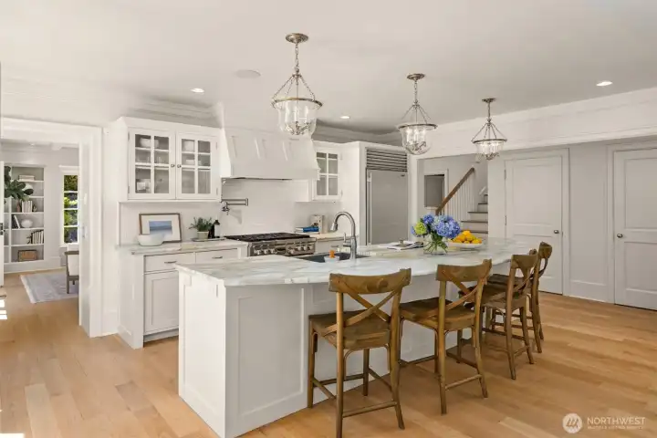 Elegant white kitchen featuring a marble-topped island and glass-front cabinetry. Elegant white kitchen featuring a marble-topped island and glass-front cabinetry.