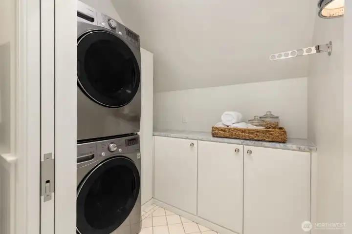 Convenient laundry room featuring a stacked washer/dryer and marble countertop storage. Convenient laundry room featuring a stacked washer/dryer and marble countertop storage.