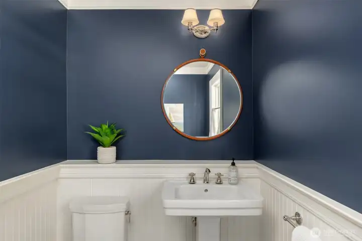Stylish powder room featuring a pedestal sink and a round mirror. Stylish powder room featuring a pedestal sink and a round mirror.