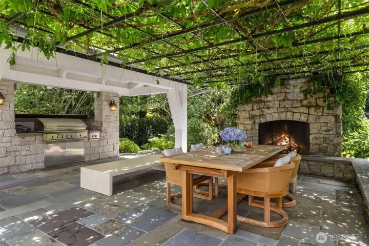 Covered outdoor living space featuring a stone fireplace and built-in grill. Covered outdoor living space featuring a stone fireplace and built-in grill.