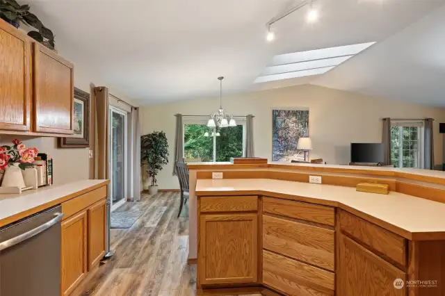 Kitchen open to dining, living areas.  Large slider to deck on left, skylights above.