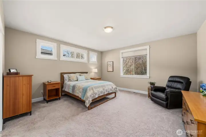 Large primary with clerestory windows above the bed and a window overlookin greenbelt