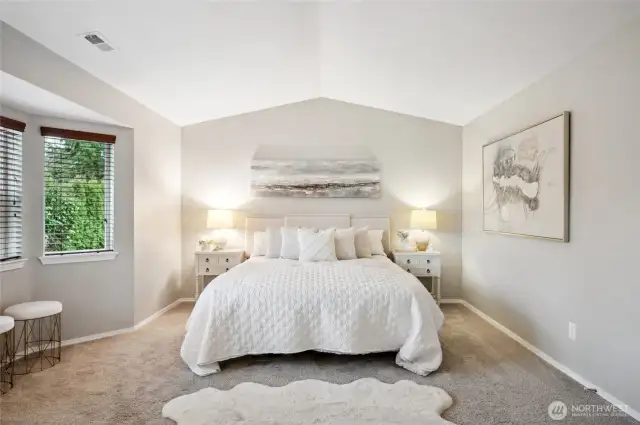 The primary bedroom boasts vaulted ceilings and bay windows.