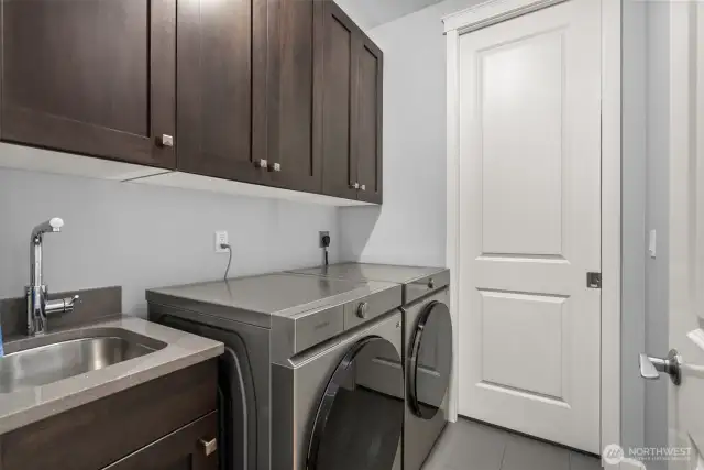 Nice to have a sink in the laundry room. The Samsong washer/dryer remain with the home. Behind the pocket door is your water heater and storage.