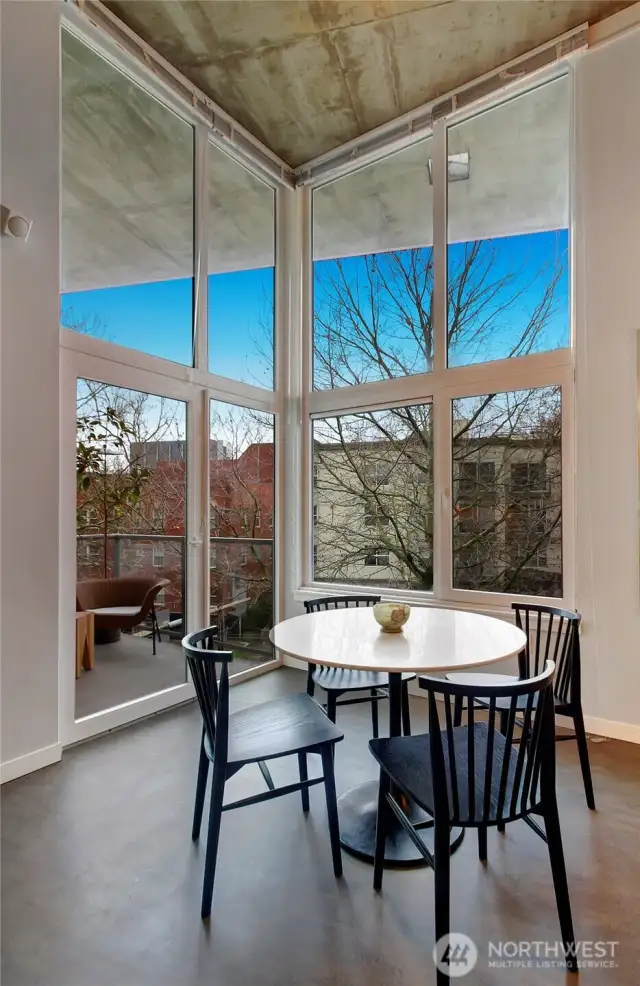 Warm western light pours through the floor-to-ceiling windows, complemented by a private deck with tree-lined and Space Needle views.