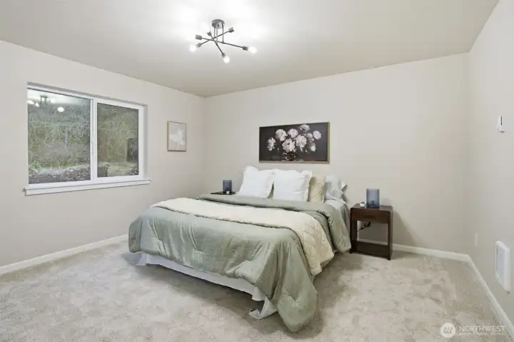 Spacious primary bedroom with large window overlooking the backyard