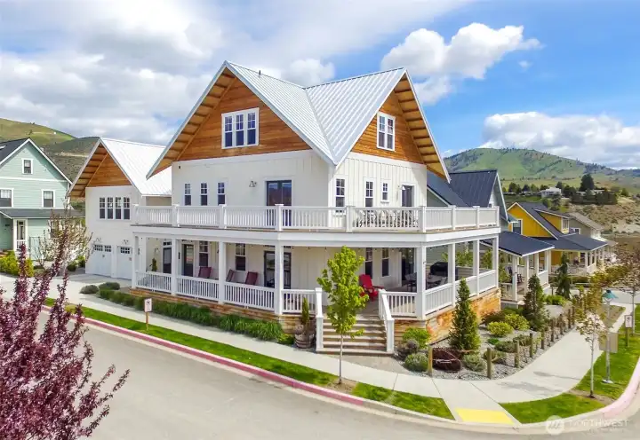 Exterior view of home with classic wraparound porch and upper level lake view decks.