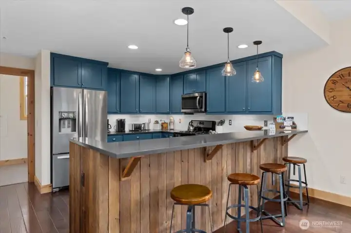 Main level kitchen with stainless steel appliances, quartz countertops and a sit up bar with vintage barn wood accents.