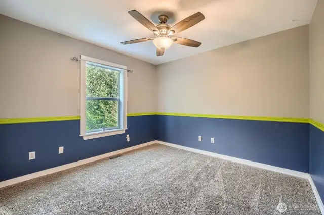 Second floor bedroom painted SeaHawk colors along back of house with window looking down into yard and onto deck with walk in closet and ceiling fan