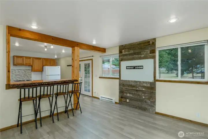 A rustic wood accent wall provides a focal point for mounting a television, while large windows fill the room with natural light and offer views of the backyard.