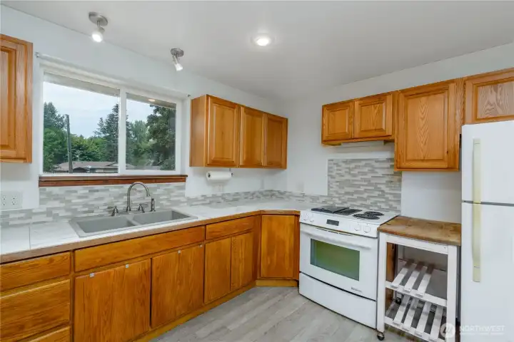 The kitchen opens seamlessly to the living area with a custom live-edge wood breakfast bar and seating for four, perfect for casual dining or entertaining.