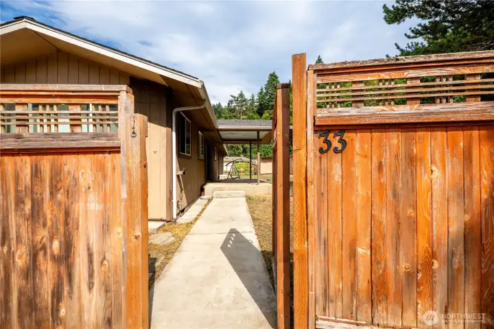 Welcoming gated entryway leading to the home’s covered patio and backyard. The wood fencing adds privacy and charm, while the concrete walkway provides easy access to the house. A private and inviting approach that enhances both security and curb appeal.